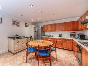 a kitchen with wooden cabinets and a wooden table and chairs at Faodail in Plockton