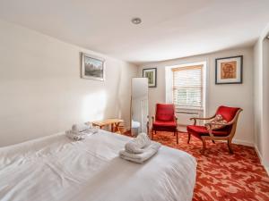 a bedroom with a white bed and two red chairs at Faodail in Plockton +15 photos