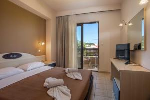a hotel room with a bed and a television and a balcony at Santa Helena Hotel in Ialysos +49 photos