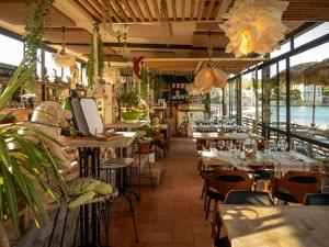 ein Restaurant mit Tischen, Stühlen und Fenstern in der Unterkunft Hotel Plein Large in Bandol