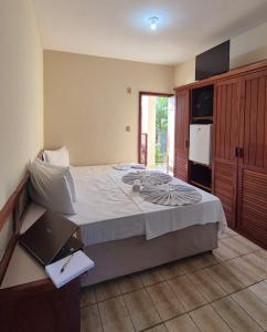 a bedroom with a large bed with a laptop on it at Pousada Enseada do Corsário in Guarapari +59 photos