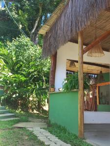 a building with a straw roof and a green wall at LahSelva Pousada e Hostel in Itacaré