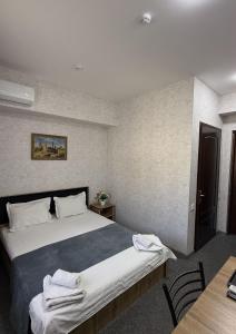 a bedroom with a large bed with two chairs and a table at Aziza Hotel White Tashkent in Yakkasaray
