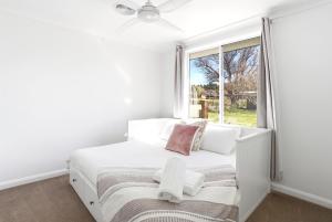 a white bedroom with a bed and a window at Blue Willow Cottage - Bathurst in Bathurst
