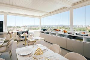 a restaurant with white tables and chairs and windows at Eleia Domos - Aurea Rooms in Monopoli