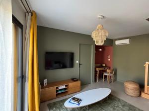 a living room with a table and a tv at Résidence les 3 volcans 4 étoiles in Clermont-Ferrand