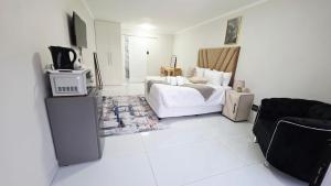 a white room with a bed and a tv at 12 On Bird BnB in Beacon Bay
