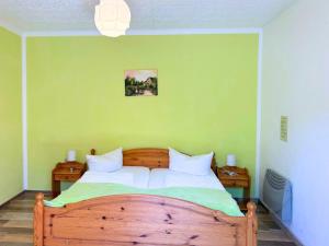 a bedroom with a wooden bed with a green wall at Hotel-Pension Am Mühlberg in Lübbenau