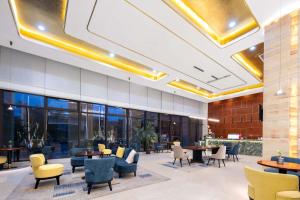 a lobby with tables and chairs in a building at ShangHai LuAn Garden Hotel-Complimentary shuttle service between Shanghai Pu d ong Airport and Disneyland in Shanghai