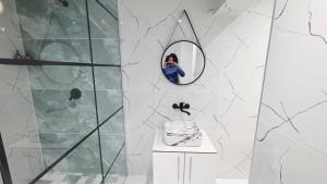 a woman taking a picture of a bathroom with a mirror at 12 On Bird BnB in Beacon Bay