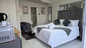 a bedroom with a large white bed and a television at 12 On Bird BnB in Beacon Bay