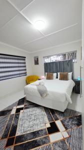 a bedroom with a large white bed and a rug at 12 On Bird BnB in Beacon Bay