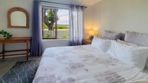 a bedroom with a large bed and a window at Paradise Beach Cottage #20 in Jeffreys Bay