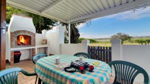 a table and chairs with a fireplace on a patio at Paradise Beach Cottage #20 in Jeffreys Bay +24 photos