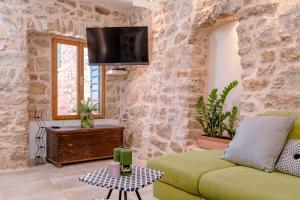 a living room with a couch and a tv on a stone wall at Stone Villa Marjan in Pitve