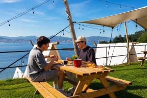 two men sitting at a picnic table under a tent at Kampaoh Ría de Vigo in Moaña