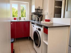 a kitchen with red cabinets and a washing machine at Chata pod Jilmy in Pelhřimov