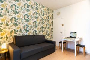 a living room with a couch and a table with a laptop at Studio LEntre Nous in Saint-Pierre-de-Chartreuse