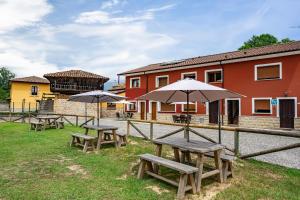 a group of picnic tables with umbrellas in front of a building at Huerta El Pozu in Soto de las Dueñas