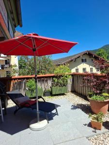 a red umbrella sitting next to a chair and a bench at Ferienwohnungen Schneiderhäusl inkl. Chiemgaukarte in Ruhpolding