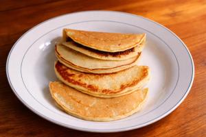 a stack of pancakes on a white plate on a table at Warna Cottage in Gili Trawangan