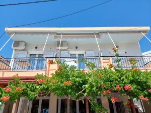 a white house with flowers on a balcony at ΠΗΛΙΟΣ ΦΩΤΙΟΣ in Loutsa