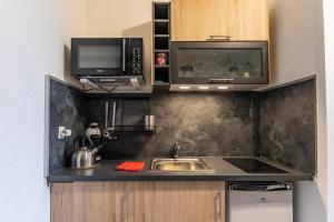 a kitchen with a sink and a microwave at Studio LEntre Nous in Saint-Pierre-de-Chartreuse