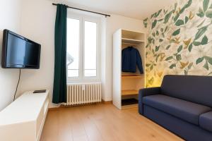 a living room with a couch and a tv at Studio LEntre Nous in Saint-Pierre-de-Chartreuse