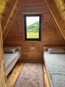 two beds in a cabin with a window at Forest View Kolašin in Kolašin