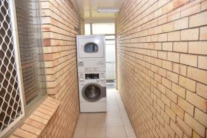 lavatrice e asciugatrice in un muro di mattoni di Chinchilla Motel a Chinchilla