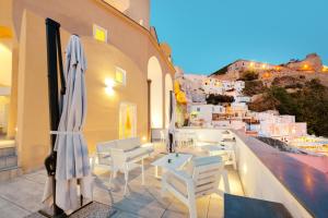 a patio with white chairs and umbrellas on a ledge at Stella di Mare in Procida
