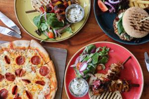a table with plates of food and pizza and salad at Marsham Court Hotel in Bournemouth