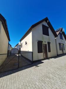 a white building with a fence in front of it at Zakątek Rumiankowa Rewal in Rewal