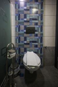a bathroom with a toilet and a tile wall at Çınar Suit Hotel in Buca +41 photos
