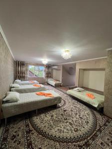 a row of beds in a room with a rug at Olzho Guest House in Karakol