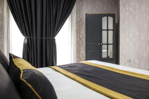 a bedroom with a bed with black and yellow curtains at Çınar Suit Hotel in Buca
