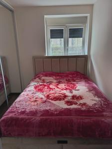 a bed with a red comforter and a window at L2 Toplica PK in Prokuplje
