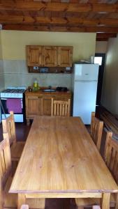 a kitchen with a wooden table and a white refrigerator at El Rancho Oliva in Molinari