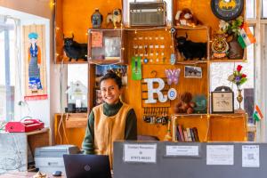a woman standing behind a desk with a laptop at Rainbow Hostelier in Leh
