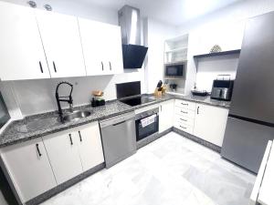 a kitchen with white cabinets and a sink at Piso en Barbate 2 dormitorios y piscina comunitaria in Barbate