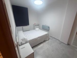 a white bedroom with a bed and a flat screen tv at Piso en Barbate 2 dormitorios y piscina comunitaria in Barbate