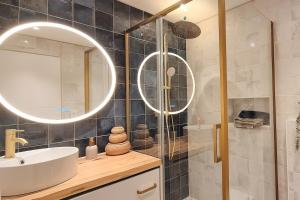a bathroom with a sink and a shower with a mirror at Le Saphir in Poligny