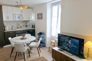 a living room with a table and chairs and a tv at Le Saphir in Poligny