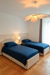 two beds in a bedroom with blue sheets and a ceiling at Le Saphir in Poligny