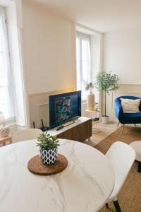 a living room with a tv and a table at Le Saphir in Poligny