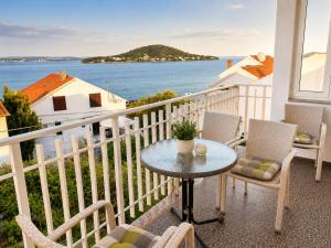 a balcony with a table and chairs and the ocean at Beachfront Summer Oasis Preko in Preko