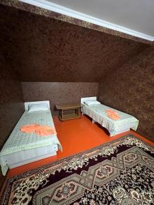 an attic room with two beds and a rug at Olzho Guest House in Karakol