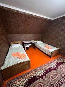 two beds in a room with two rugs at Olzho Guest House in Karakol