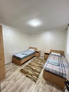 a room with two beds and a rug at Kabyl Guest House in Tossor