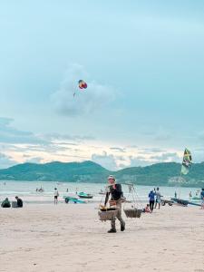 a man standing on a beach flying a kite at Vibes Solution in Patong Beach